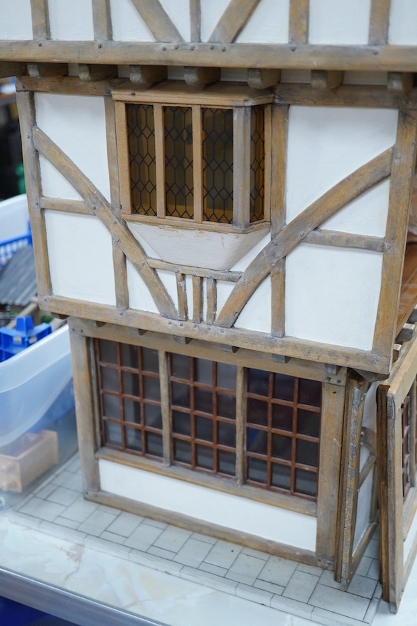 A modern doll’s house in the form of an oak framed Tudor house on three floors, with a shop on the ground floor, removable front panels on each floor and one side of the roof, with internal detailing and a good selection